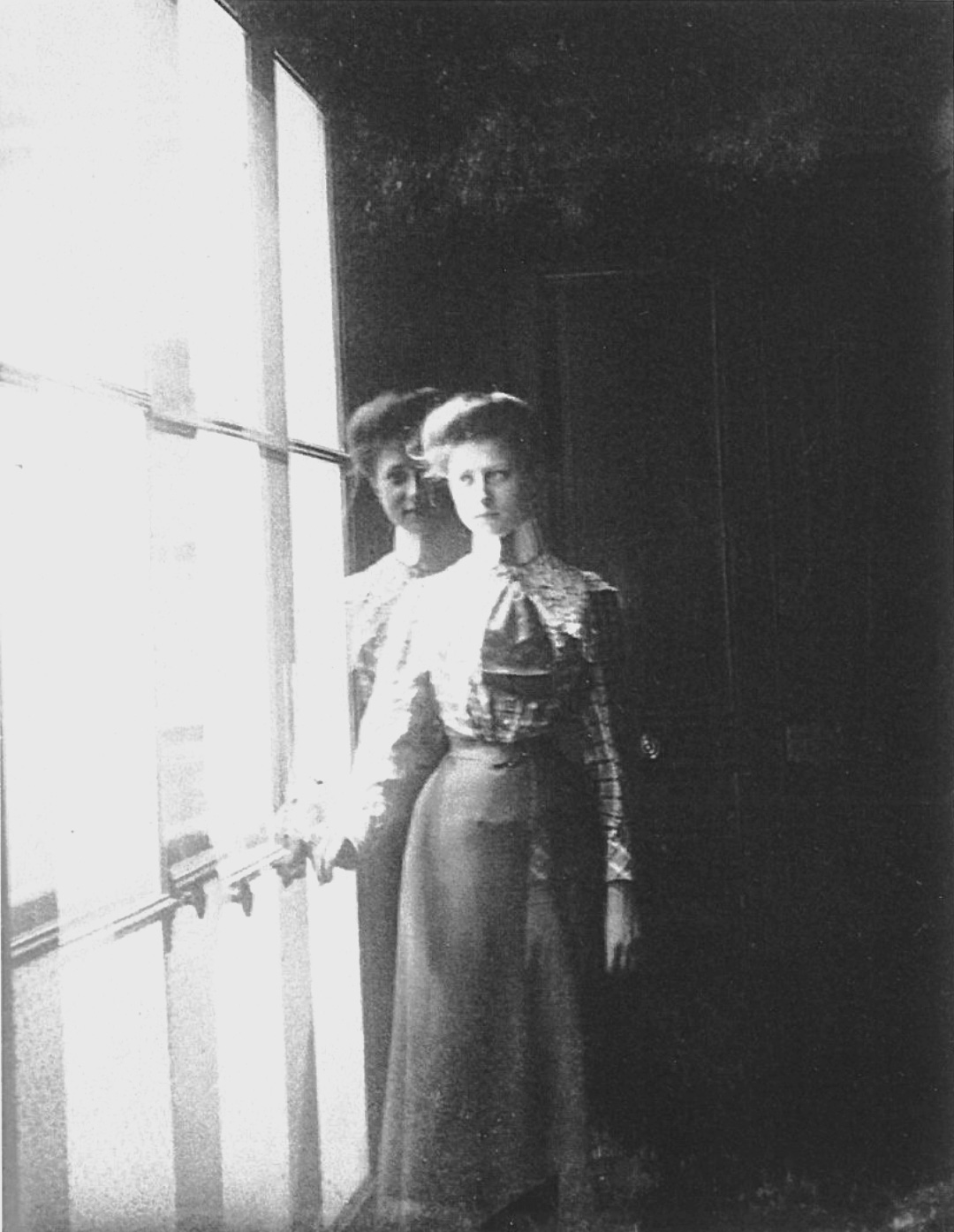 Fotografía de una mujer antigua y elegante en una ventana con doble exposición. Este tipo de fotografías se utilizó mucho como fotografía espiritista por embaucadores en los inicios de la fotografía.